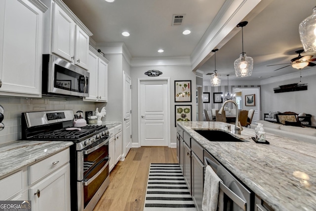 kitchen with visible vents, open floor plan, white cabinets, a sink, and stainless steel appliances