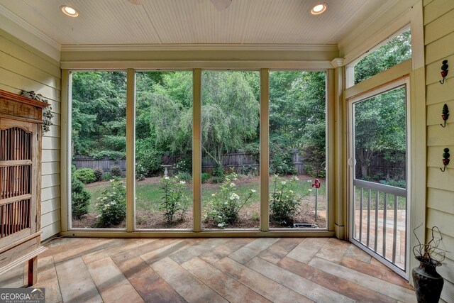 unfurnished sunroom featuring crown molding, recessed lighting, and wood walls
