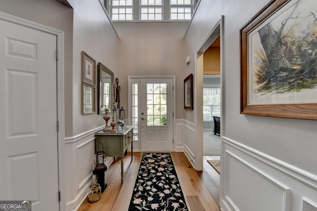 foyer featuring a wainscoted wall, a decorative wall, and light wood-style flooring
