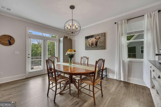 dining room with visible vents, crown molding, wood finished floors, baseboards, and an inviting chandelier
