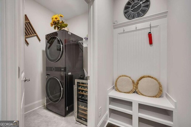 laundry room featuring wine cooler, baseboards, laundry area, and stacked washer / dryer