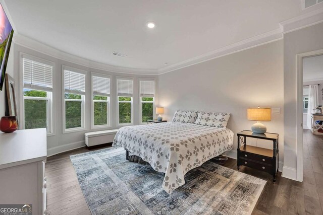 bedroom with crown molding, baseboards, wood finished floors, and visible vents