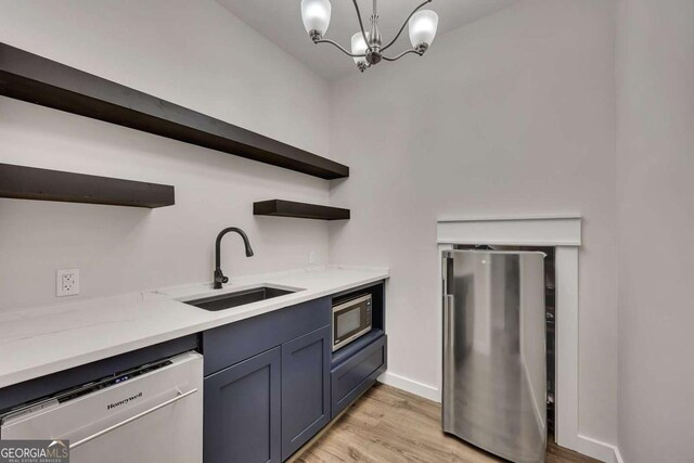 kitchen featuring open shelves, a sink, light wood-style flooring, a notable chandelier, and stainless steel appliances