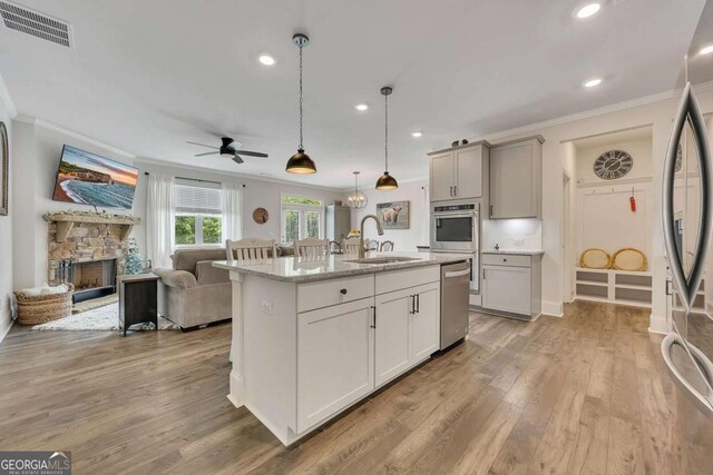kitchen featuring crown molding, a sink, stainless steel appliances, open floor plan, and visible vents