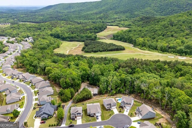drone / aerial view featuring view of golf course, a view of trees, a mountain view, and a residential view