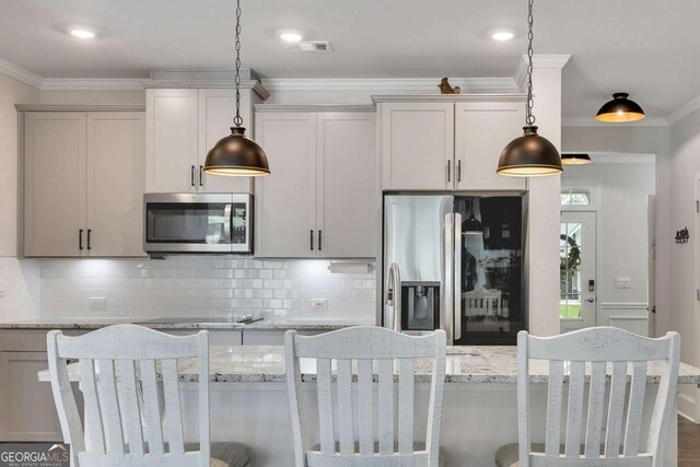 kitchen featuring light stone countertops, stainless steel appliances, decorative light fixtures, tasteful backsplash, and ornamental molding