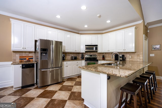 kitchen featuring decorative backsplash, a sink, a peninsula, stainless steel appliances, and white cabinetry