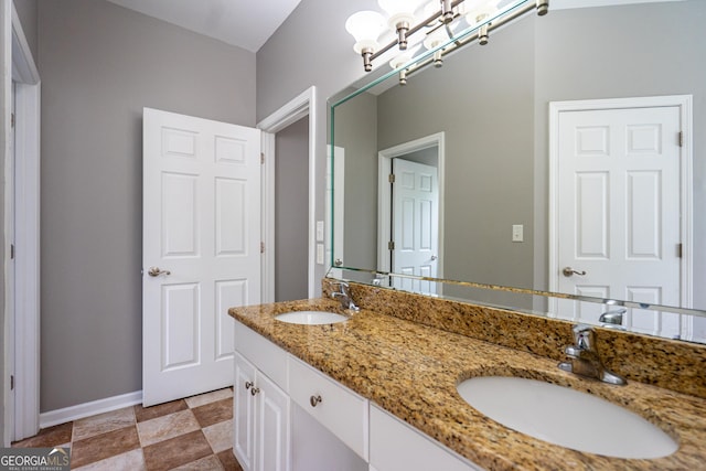 bathroom with baseboards, a sink, a notable chandelier, and double vanity