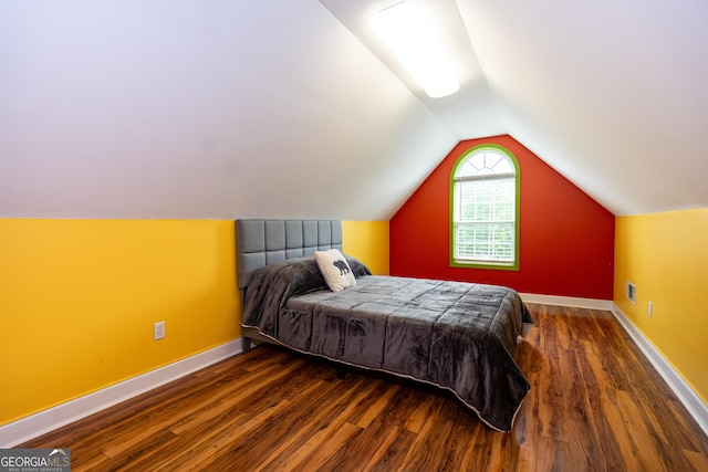 bedroom with baseboards, vaulted ceiling, wood finished floors, and visible vents