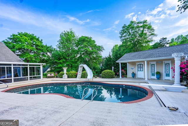pool featuring a sunroom, a diving board, a patio area, and a water slide