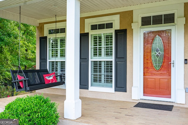 doorway to property with covered porch and stucco siding