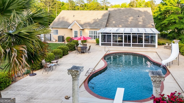 outdoor pool with central air condition unit, a patio, a water slide, and a sunroom