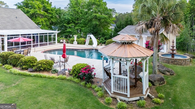 pool with a lawn, fence, a water slide, and a patio area