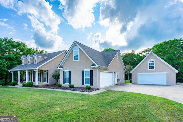 view of front of property featuring a front lawn, covered porch, stucco siding, driveway, and a detached garage