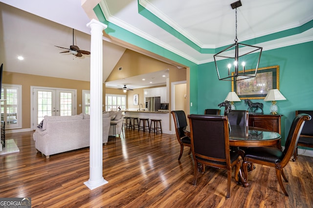 dining space with decorative columns, vaulted ceiling, wood finished floors, baseboards, and ceiling fan with notable chandelier