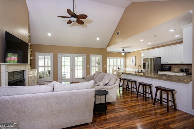 living area with ceiling fan, dark wood-style floors, high vaulted ceiling, and a fireplace