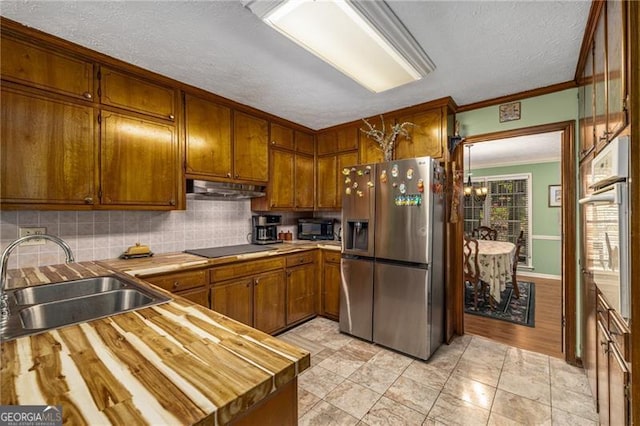 kitchen featuring crown molding, brown cabinets, a sink, black appliances, and under cabinet range hood