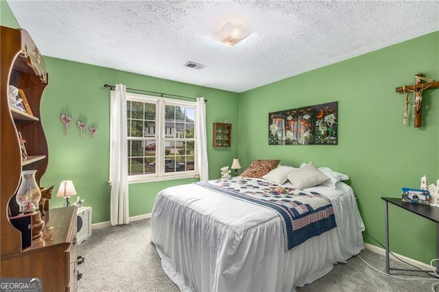 bedroom featuring a textured ceiling, visible vents, baseboards, and carpet