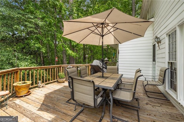 deck with outdoor dining space and a grill