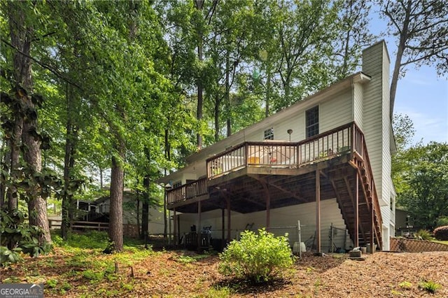 back of property featuring a chimney, stairs, and a deck
