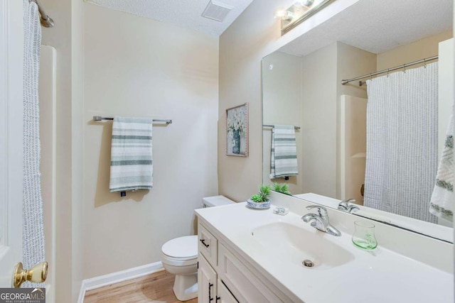 full bathroom with visible vents, vanity, wood finished floors, toilet, and baseboards