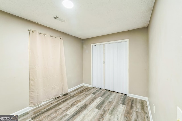 unfurnished bedroom with visible vents, baseboards, and wood finished floors