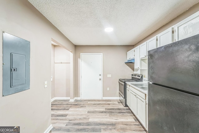 kitchen with freestanding refrigerator, under cabinet range hood, electric panel, stainless steel electric stove, and light wood-style flooring