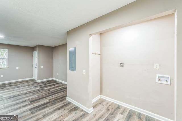interior space featuring baseboards, a textured ceiling, wood finished floors, and electric panel
