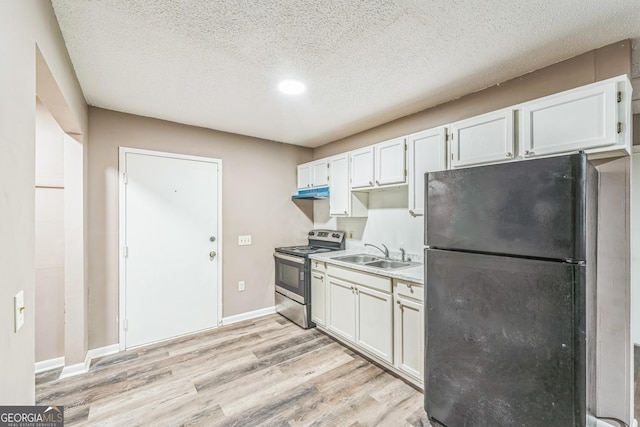 kitchen featuring freestanding refrigerator, electric range, a textured ceiling, a sink, and light wood-style flooring