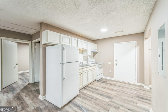 kitchen with a sink, light wood finished floors, white appliances, white cabinetry, and visible vents