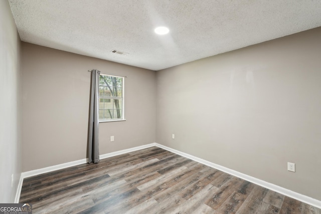 spare room with baseboards, a textured ceiling, visible vents, and wood finished floors
