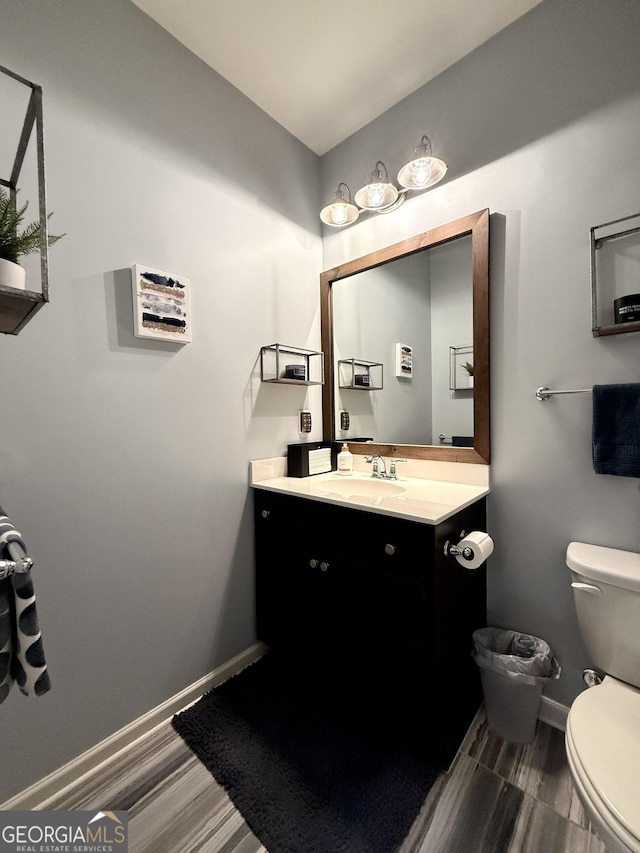 bathroom featuring baseboards, vanity, and toilet