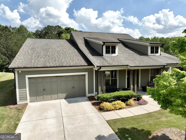 view of front of property with a garage, covered porch, a front yard, roof with shingles, and concrete driveway