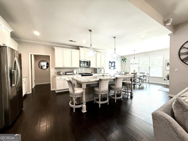 kitchen featuring ornamental molding, baseboards, a kitchen bar, white cabinets, and stainless steel appliances