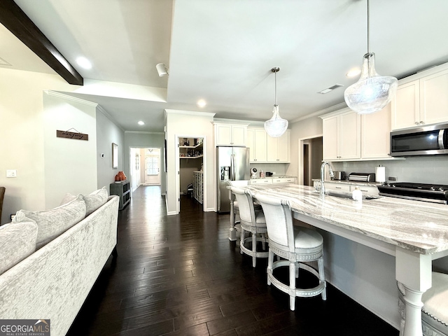 kitchen featuring a large island, crown molding, a sink, open floor plan, and stainless steel appliances