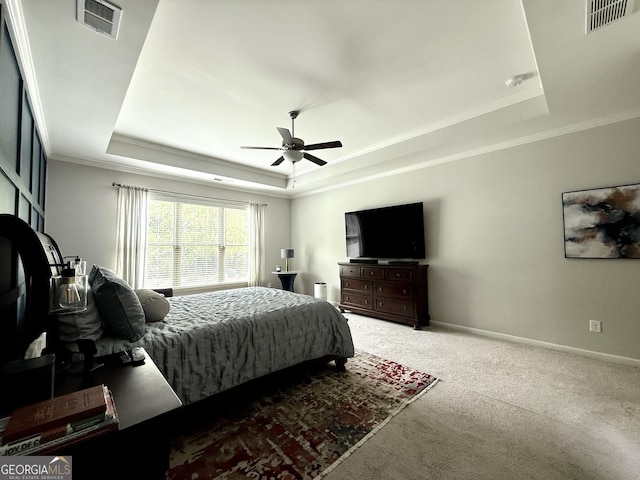 carpeted bedroom featuring crown molding, a raised ceiling, baseboards, and visible vents