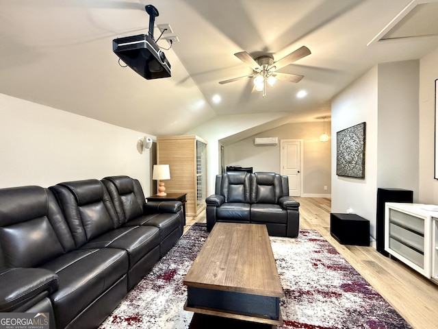 cinema room with a ceiling fan, a wall mounted AC, lofted ceiling, and light wood-style floors