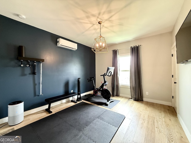exercise room featuring an AC wall unit, baseboards, wood finished floors, and a chandelier