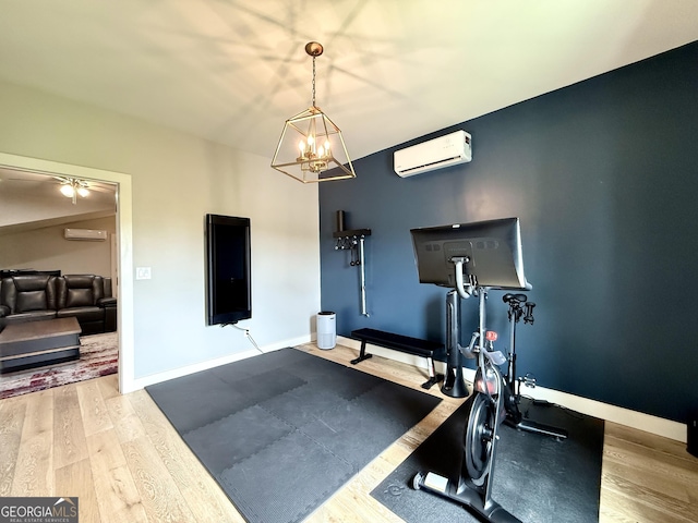 exercise area featuring a wall mounted AC, wood finished floors, and a chandelier