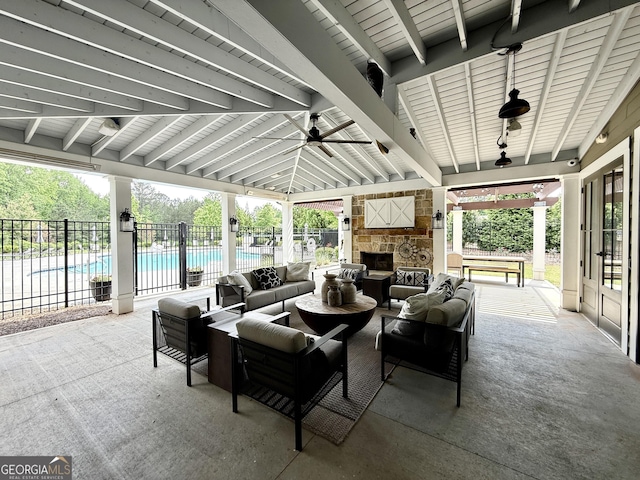 view of patio / terrace with fence, a ceiling fan, an outdoor living space with a fireplace, and a gazebo