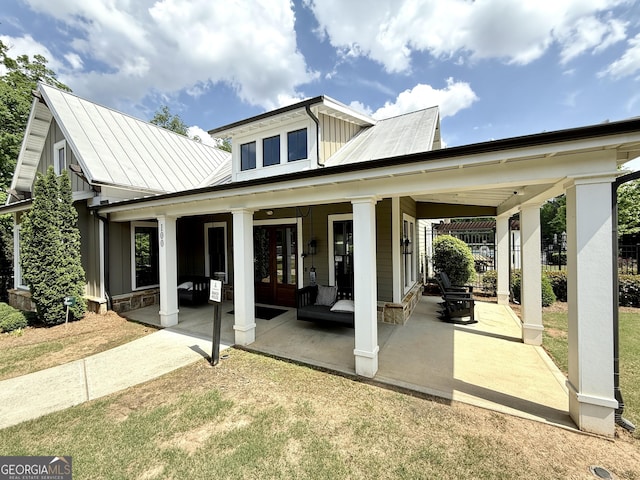 back of house with board and batten siding, a patio, a standing seam roof, and metal roof