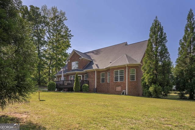 exterior space with a lawn, a wooden deck, and brick siding