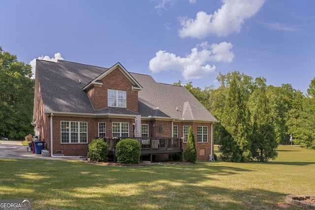 rear view of house with brick siding, a wooden deck, and a yard