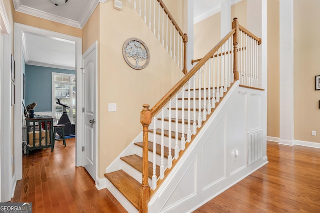 stairway featuring crown molding, baseboards, visible vents, and wood finished floors