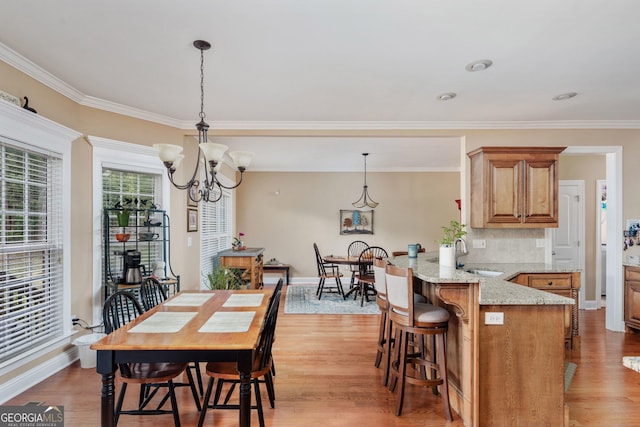 dining area with crown molding, baseboards, a notable chandelier, and light wood-type flooring