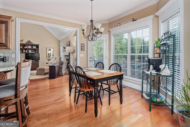 dining room featuring light wood-style floors, crown molding, and a notable chandelier