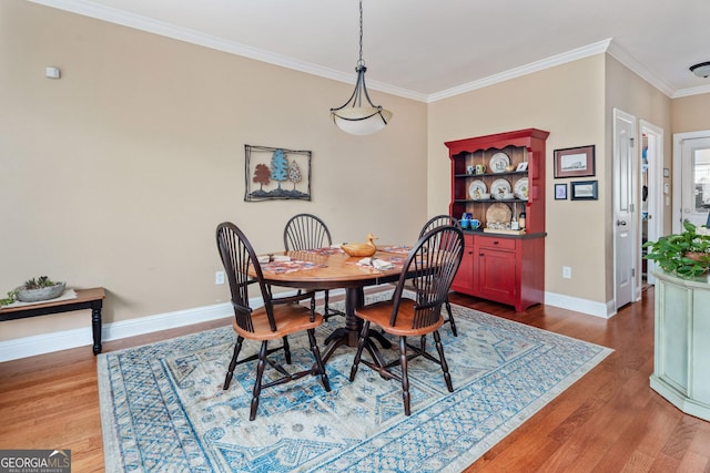 dining area with baseboards, ornamental molding, and wood finished floors