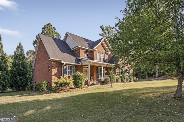 craftsman house featuring covered porch, a front yard, and brick siding