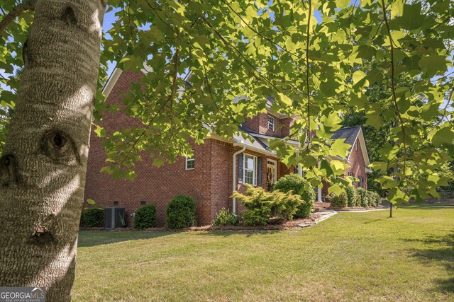 view of home's exterior with a yard, central AC, and brick siding