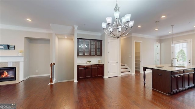 kitchen with a sink, a breakfast bar area, dark wood-type flooring, pendant lighting, and baseboards